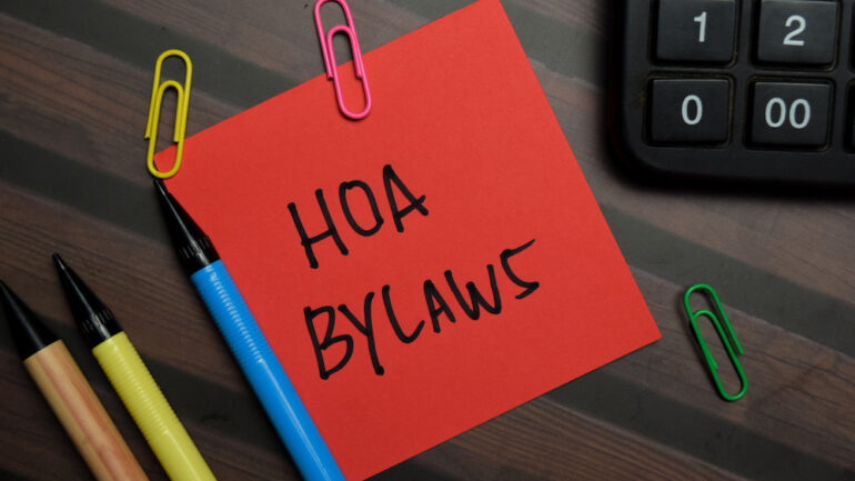 HOA Bylaws are written on sticky notes isolated on a wooden table. Also includes the Architectural Control Committee.