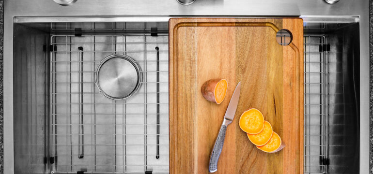 Workstation kitchen sink with cutting board used to slice a sweet potato