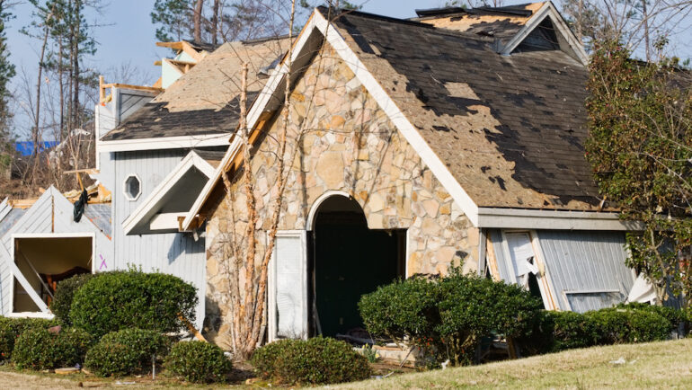 The roof of this wood frame and stone house was destroyed by this natural disaster. A reputable roofing contractor is needed for repairs.