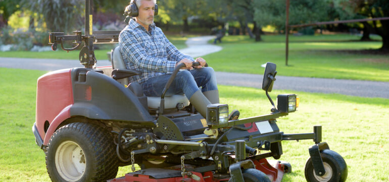 Ground maintenance man using a zero-turn lawnmower to cut the grass of a large property.