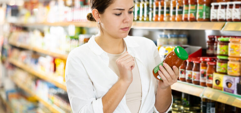 nterested female shopper examining food expiration dates on labels in a supermarket.