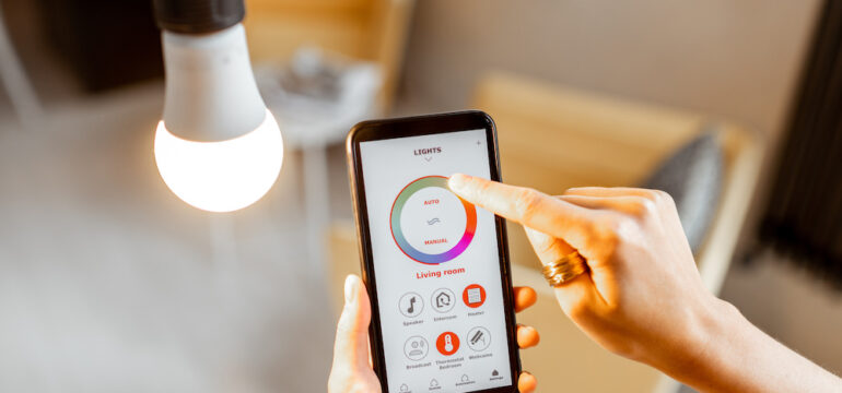 Controlling smart light bulbs temperature and intensity with a smartphone application. Concept of a smart home and managing light with mobile devices.
