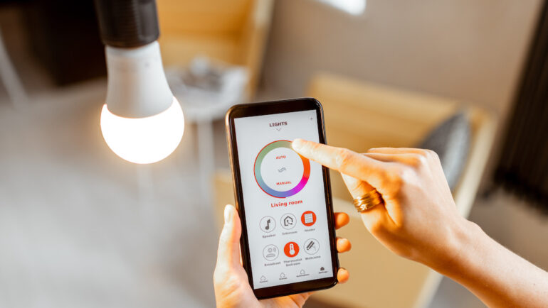 Controlling smart light bulbs temperature and intensity with a smartphone application. Concept of a smart home and managing light with mobile devices.