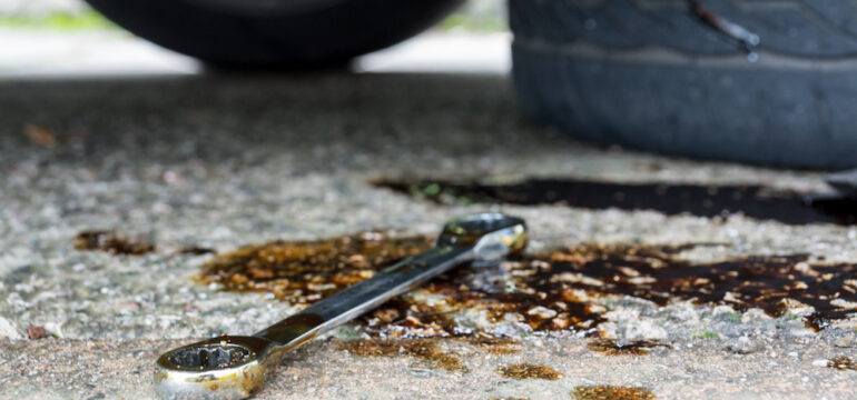 A socket wrench was left on the floor in a puddle of oil stains.