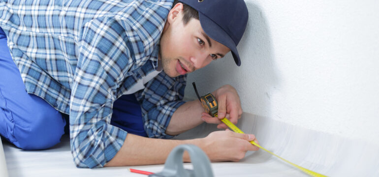 Appraiser measuring square footage in an unfinished room in a new house.