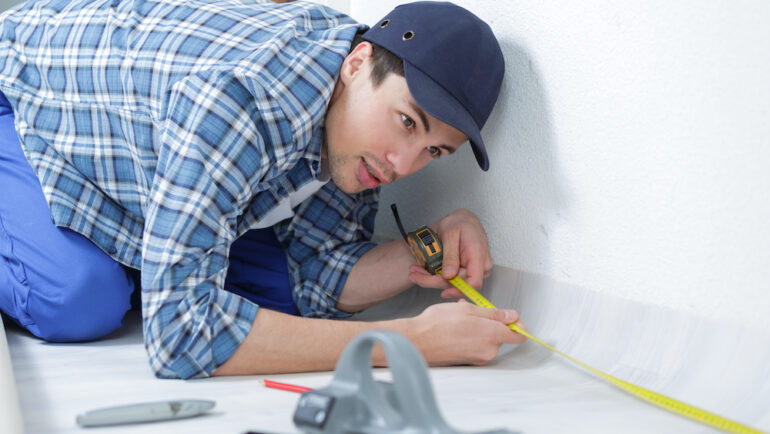 Appraiser measuring square footage in an unfinished room in a new house.