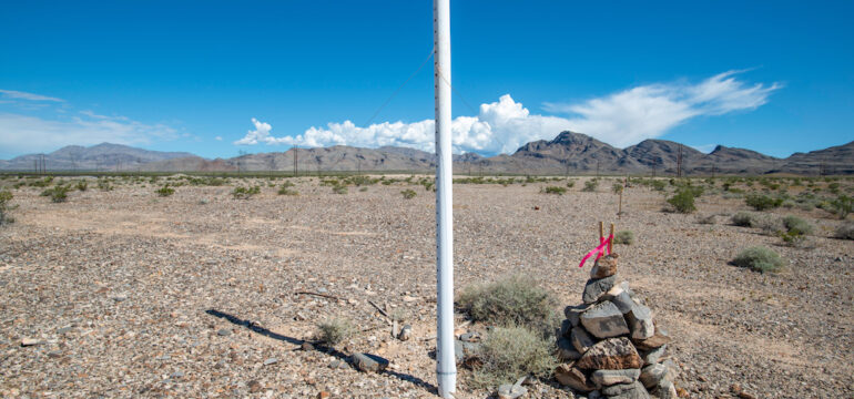 A white PVC marker and rock cairn established at a Township Range and Section Corner of a federal land parcel.