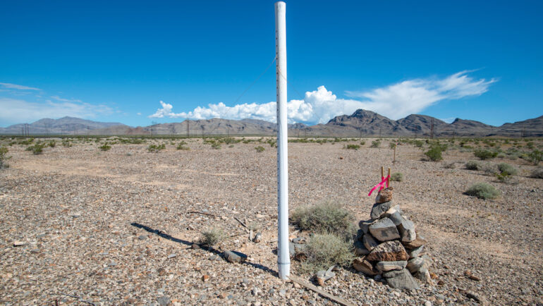 A white PVC marker and rock cairn established at a Township Range and Section Corner of a federal land parcel.