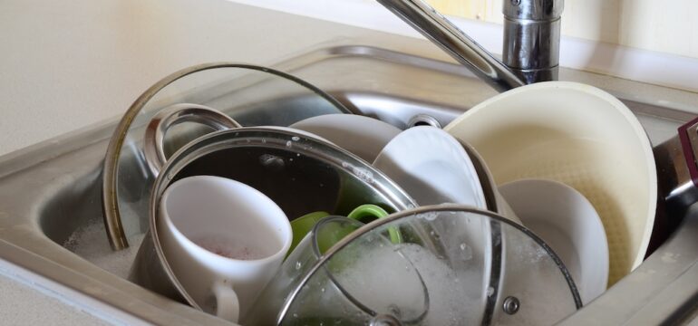 Soaking dishes and unwashed kitchen utensils in a full kitchen sink.