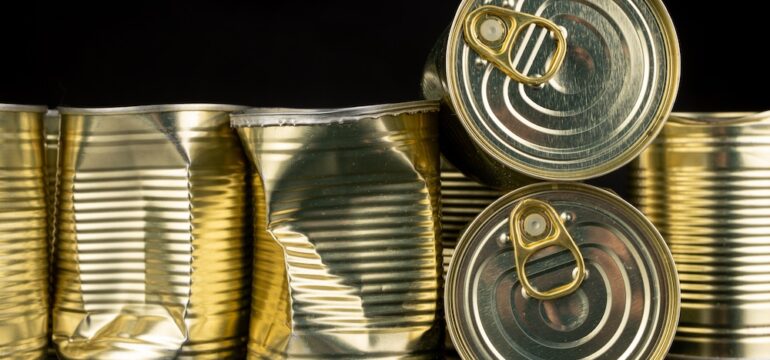 Dented canned food with vegetables on a wooden table.