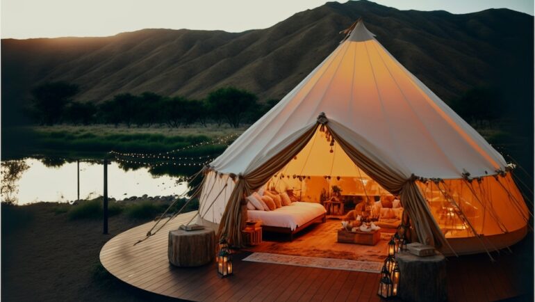 Luxury tent with bed near a lake to invision the health benefits of sleeping outdoors.